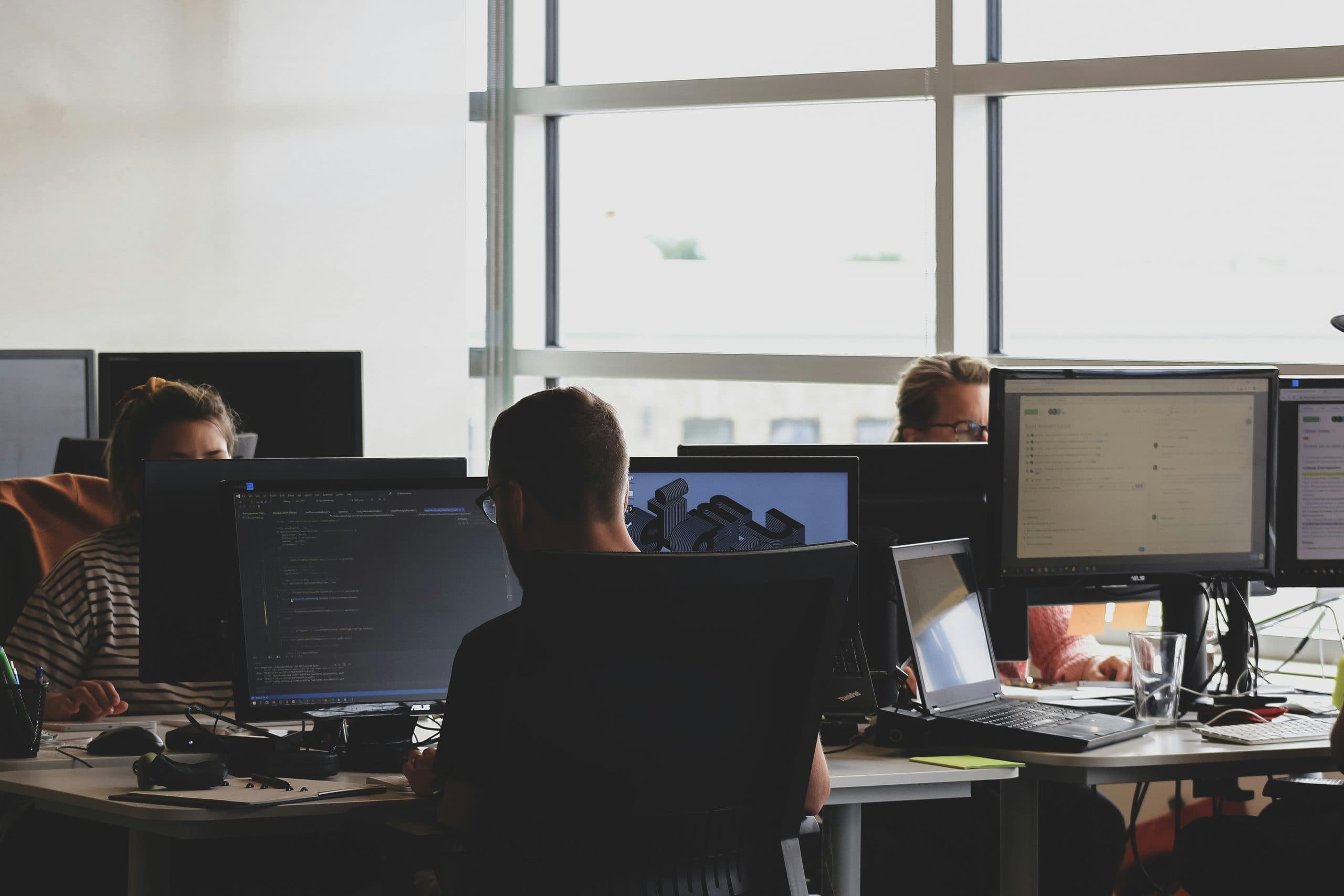 Techniciens en open-space devant leurs écrans